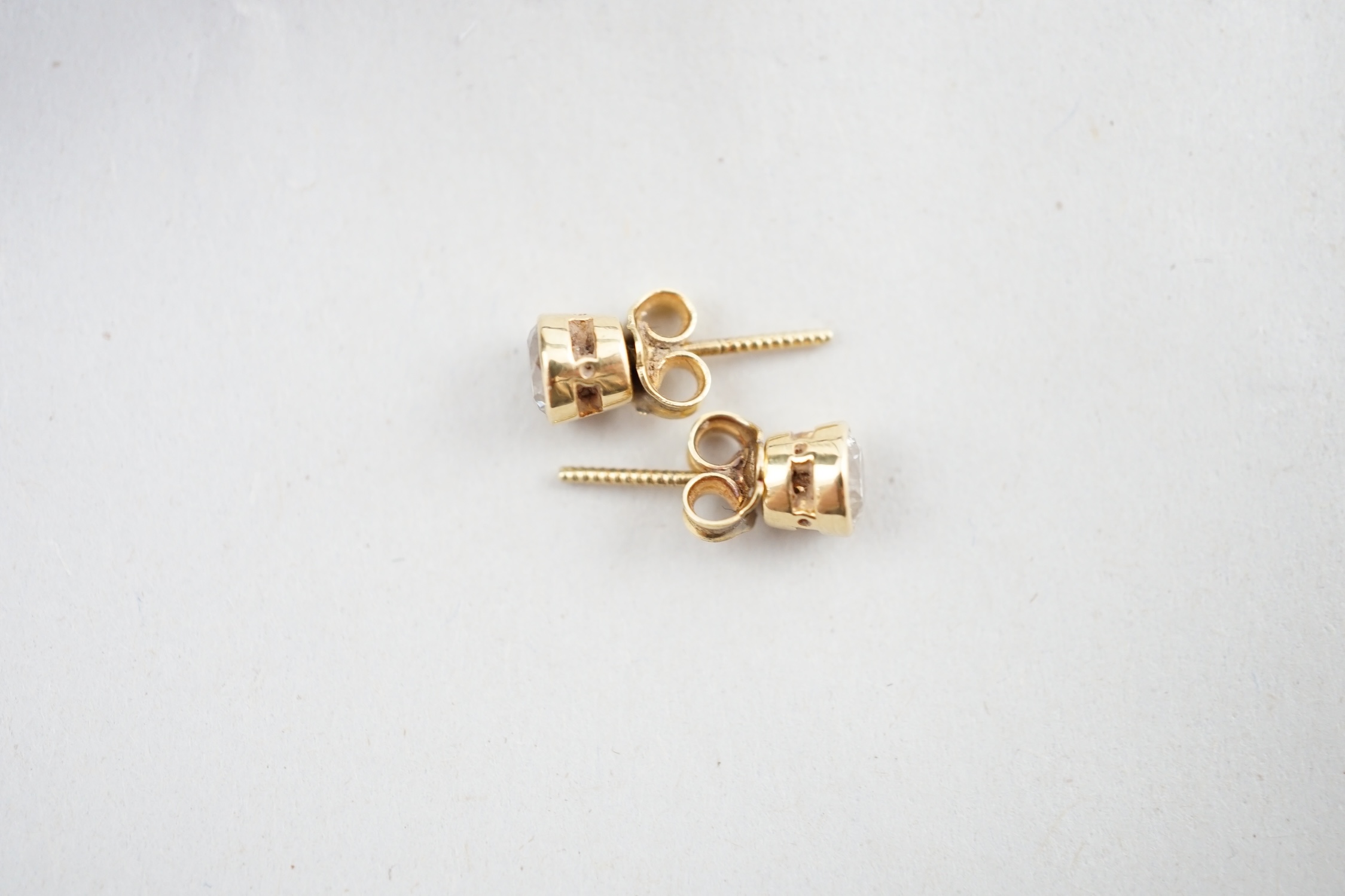 A pair of 18ct gold and collet set solitaire diamond ear studs